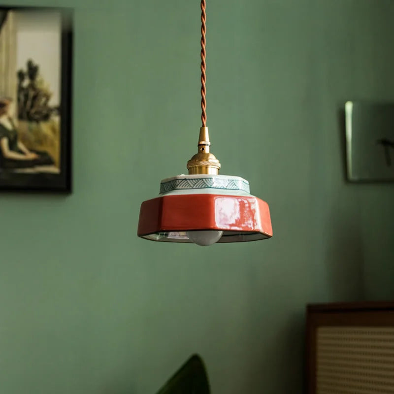 Red pendant light hanging against a green wall